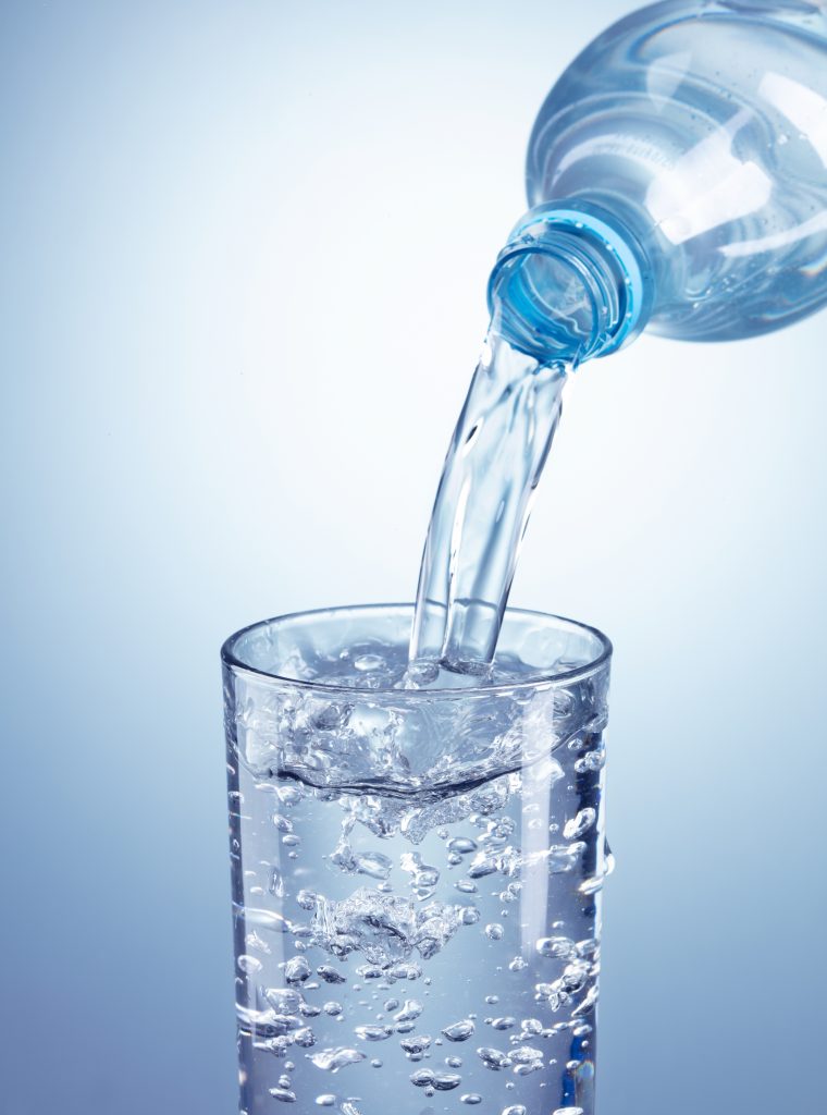 pouring water from plastic bottle into glass